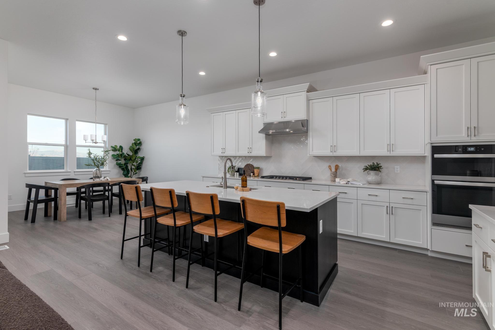 8520 West Fanning Street Star, ID 83669 - Photo 4 of 11 Kitchen with dark cabinets, hanging light fixtures, tasteful backsplash, white cabinets, and recessed lighting