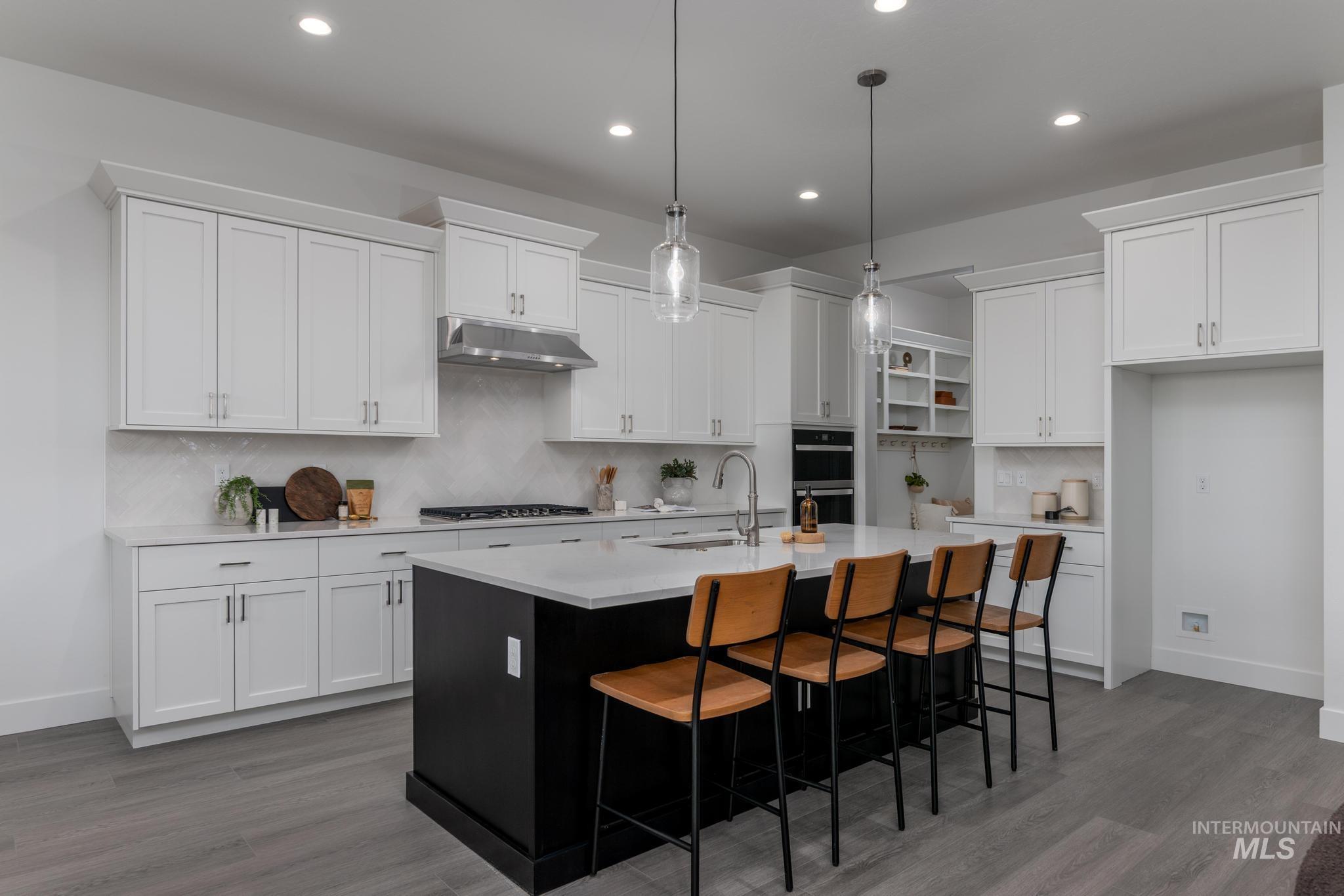 8520 West Fanning Street Star, ID 83669 - Photo 5 of 11 Kitchen with dark cabinets, backsplash, a center island with sink, decorative light fixtures, and recessed lighting