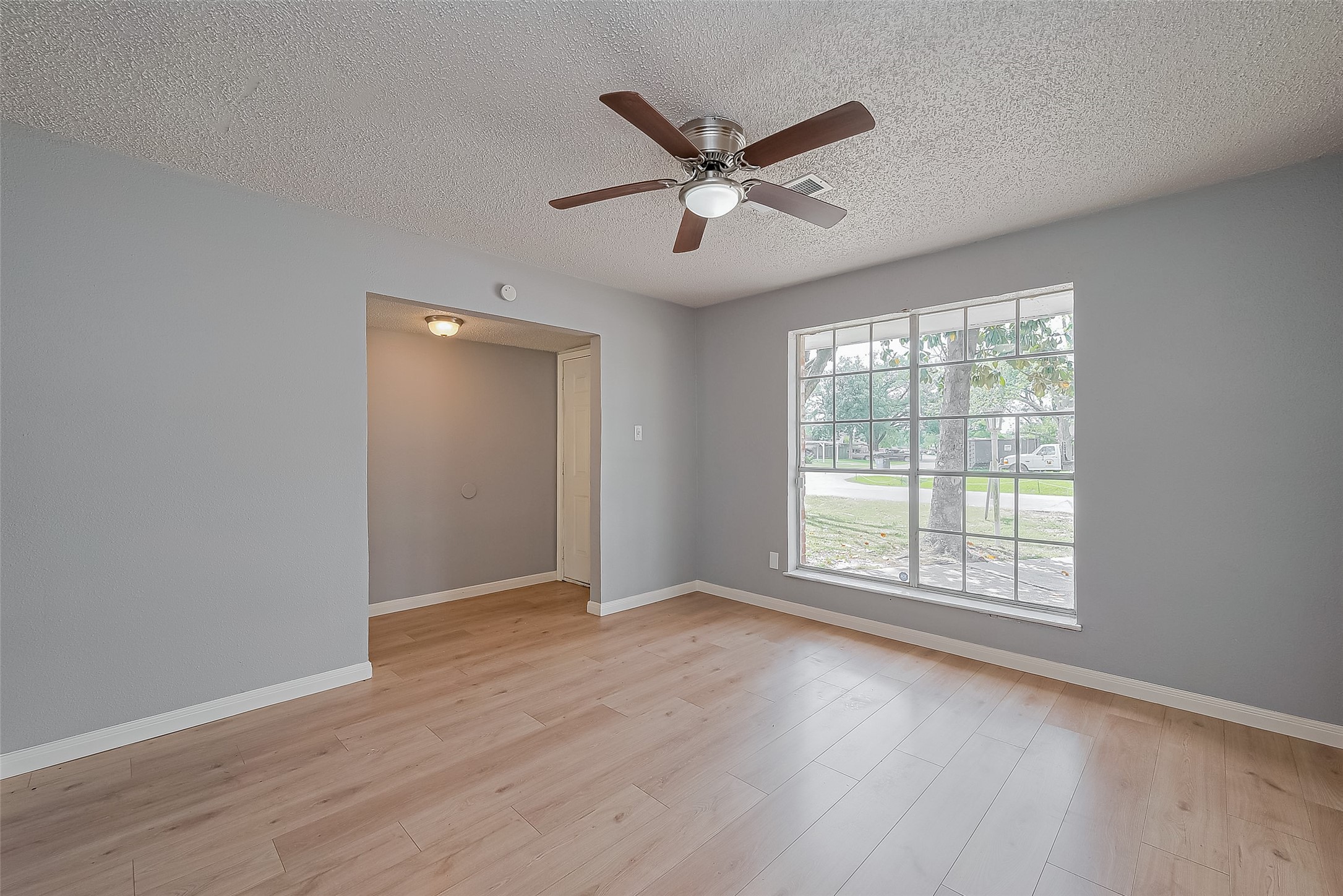 206 Beaver Bend Road Houston, TX 77037 - Photo 12 of 38 an empty room with wooden floor fan and windows