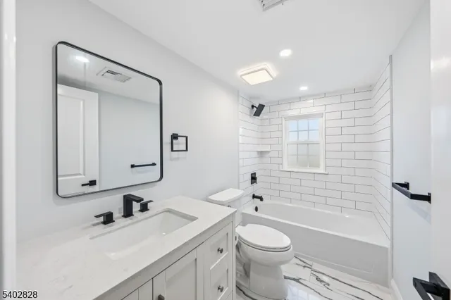 a bathroom with a bathtub shower sink vanity mirror and toilet