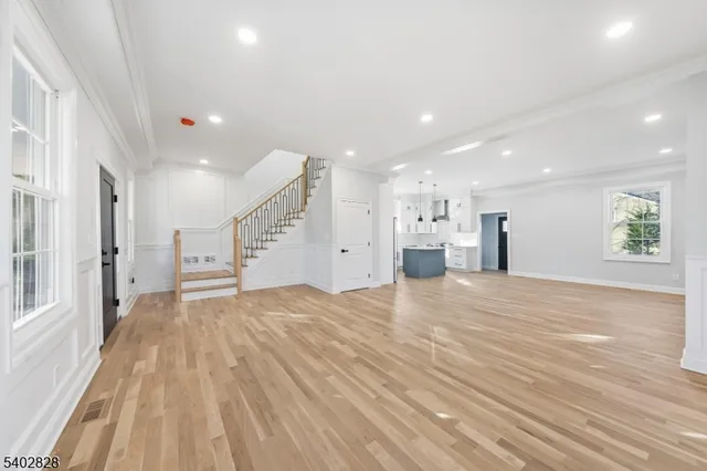a view of an empty room and kitchen with furniture wooden floor and window