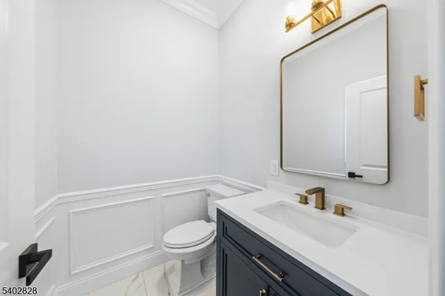a bathroom with a granite countertop sink vanity mirror and toilet
