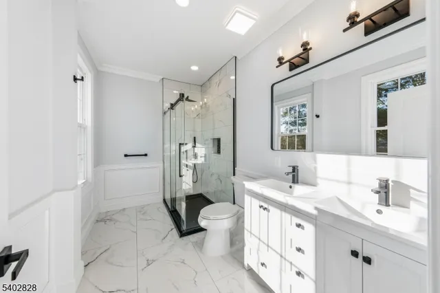 a spacious bathroom with a double vanity sink toilet mirror and shower