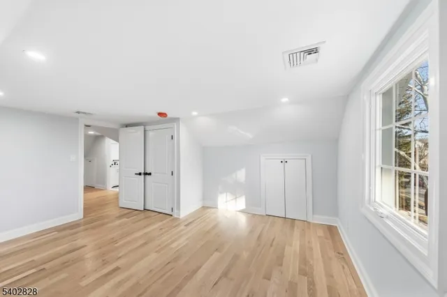 a view of a big room with wooden floor and windows