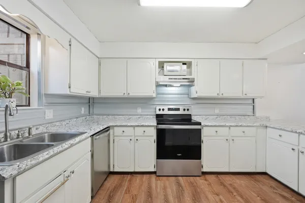 a kitchen with cabinets stainless steel appliances a sink and wooden floor