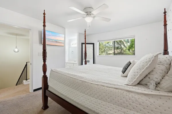 a bedroom with a bed next to a window with a chandelier