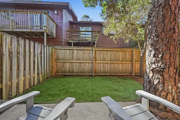 a view of backyard with wooden fence and large trees