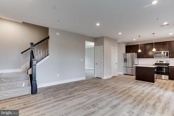a view of an empty room with wooden floor and stairs