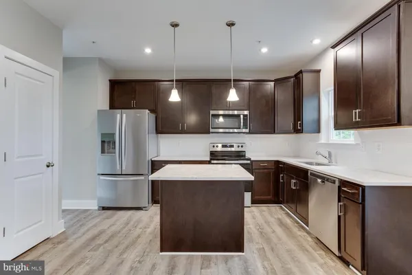 a open kitchen with a sink a center island and wooden floor