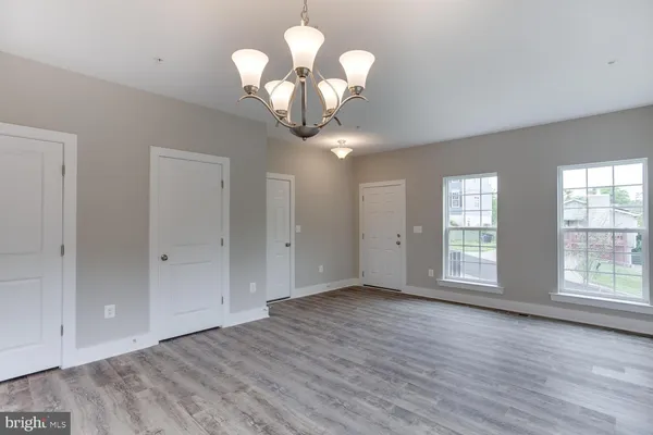 a view of an empty room with wooden floor and kitchen space