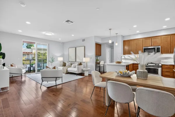 a living room with furniture kitchen view and a large window