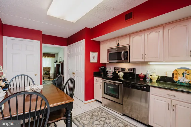 a kitchen with stainless steel appliances granite countertop a stove a sink dishwasher a dining table and chairs with wooden floor