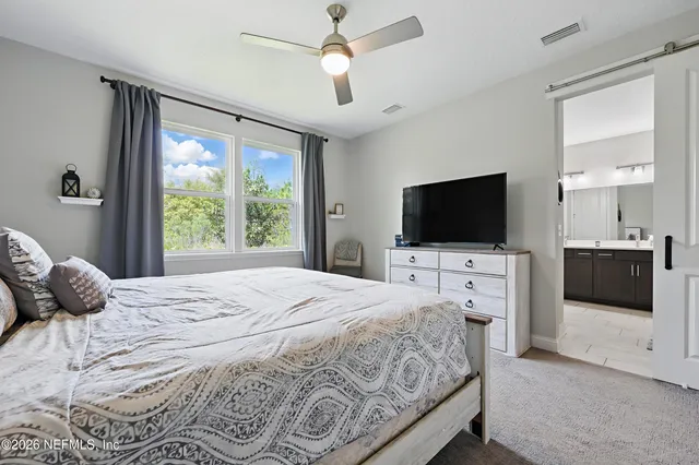 a bedroom with a large bed and a flat tv screen on dresser