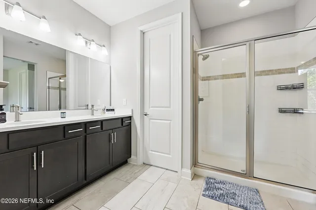 a bathroom with a double vanity sink a mirror and a shower
