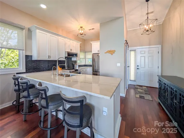 a kitchen with stainless steel appliances granite countertop a sink a stove a dining table and chairs