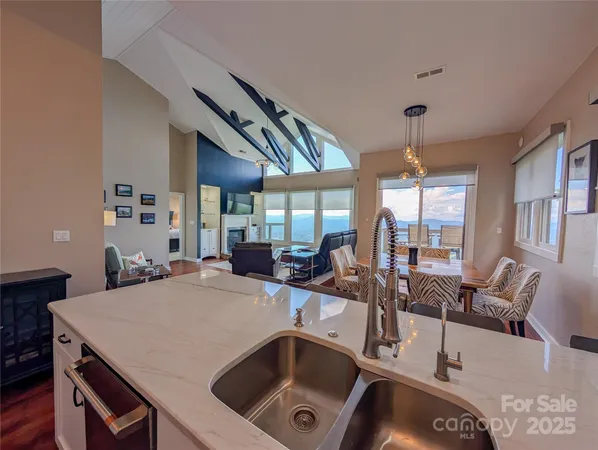 a kitchen with a stove a sink dishwasher a dining table and chairs with wooden floor
