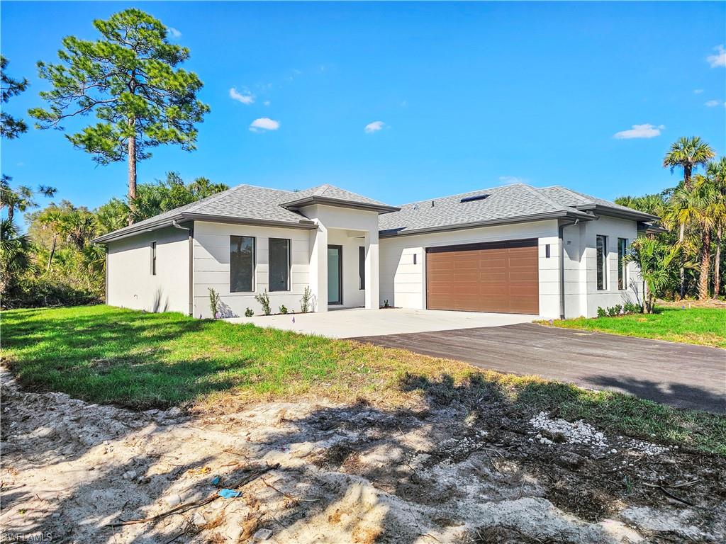 2997 28th Avenue Southeast Naples, FL 34117 - Photo 2 of 49 a front view of a house with a garden and yard