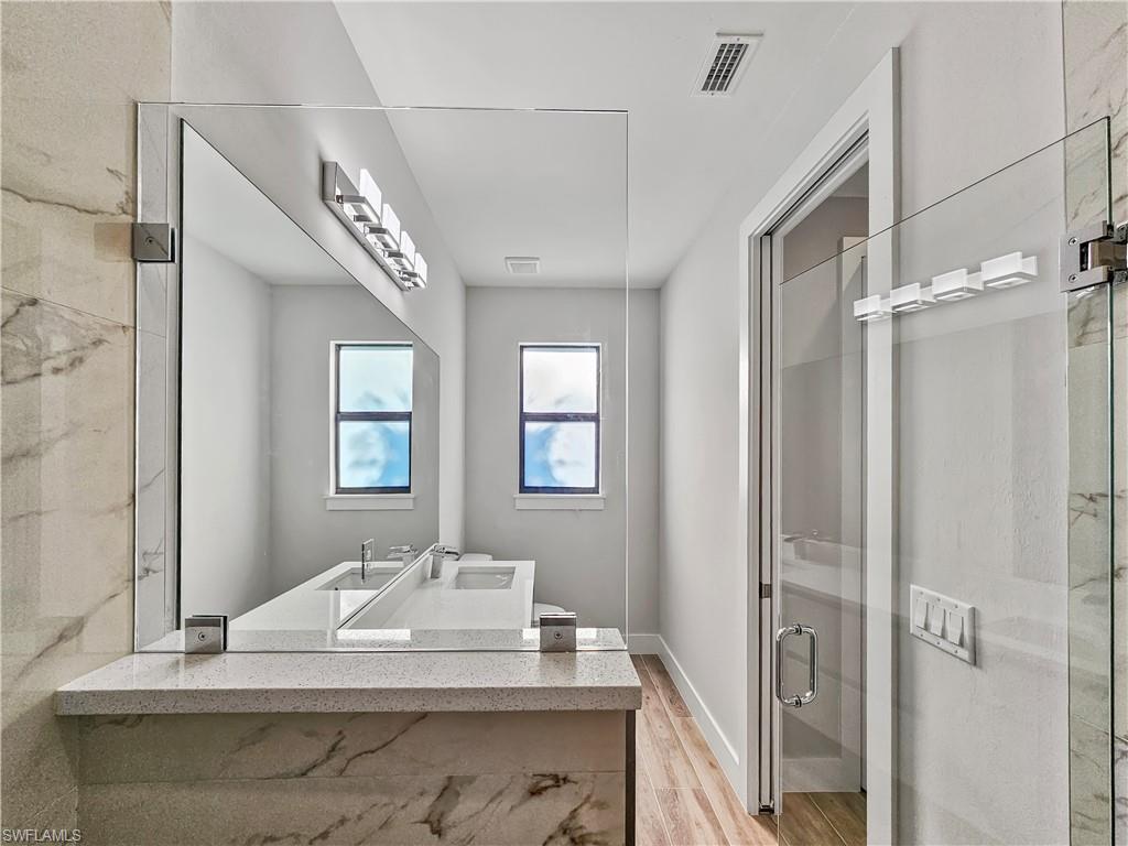 2997 28th Avenue Southeast Naples, FL 34117 - Photo 27 of 49 a bathroom with a granite countertop sink a mirror and shower