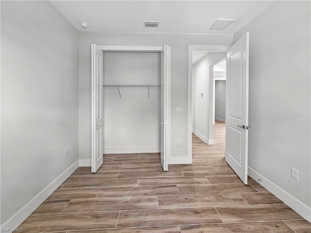 2997 28th Avenue Southeast Naples, FL 34117 - Photo 39 of 49 a view of an empty room with wooden floor and a bathroom