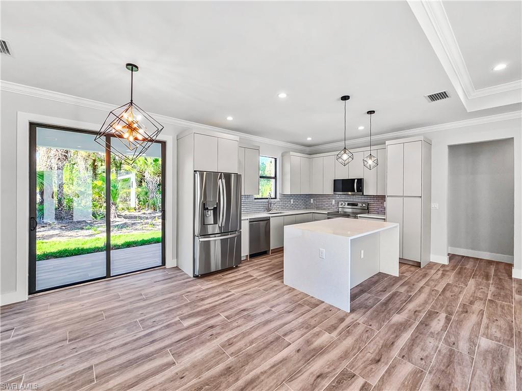 2997 28th Avenue Southeast Naples, FL 34117 - Photo 5 of 49 a kitchen that has a lot of white cabinets and stainless steel appliances
