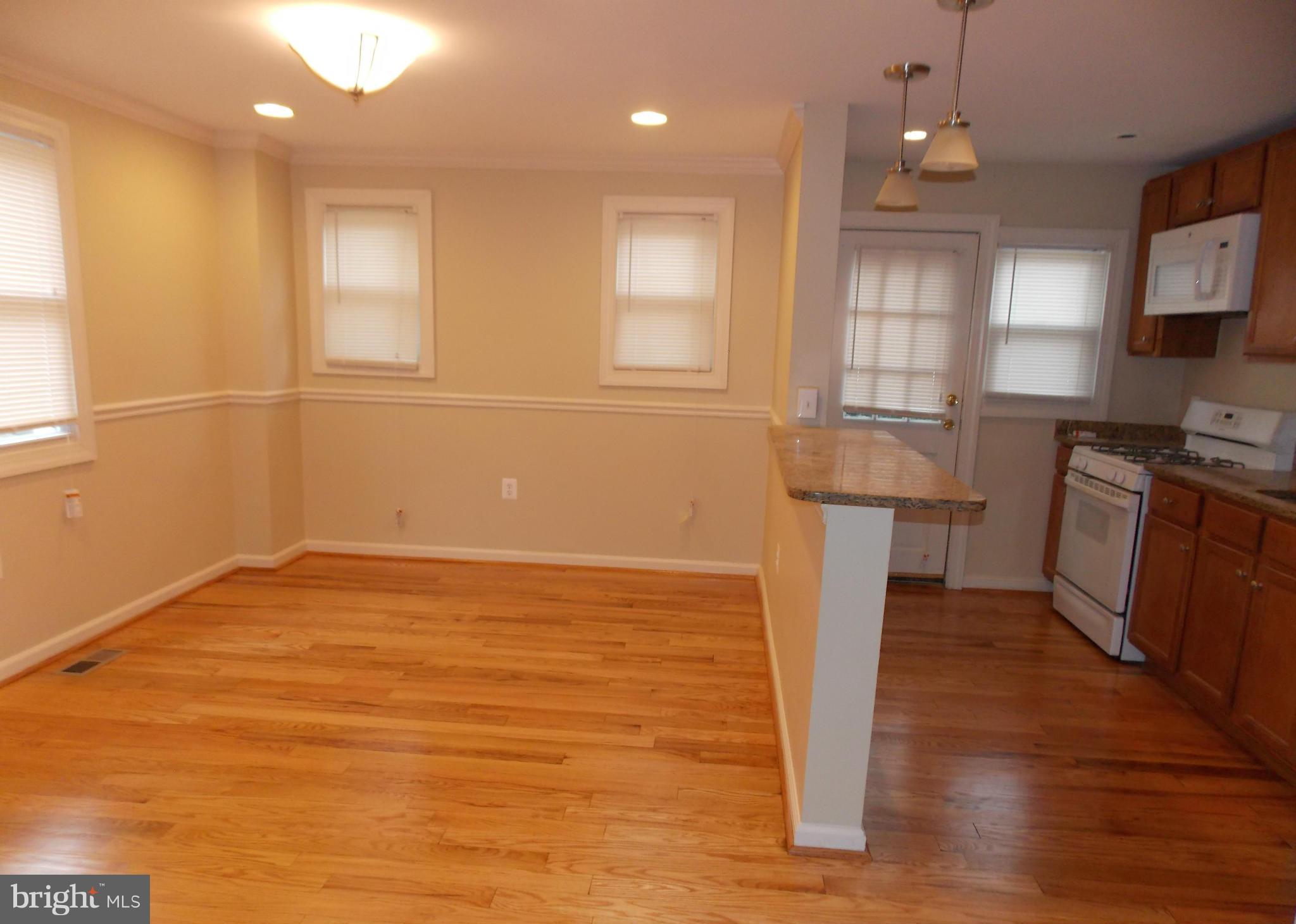 754 Charing Cross Road Baltimore, MD 21229 - Photo 5 of 15 a view of kitchen and empty room with wooden floor and fan