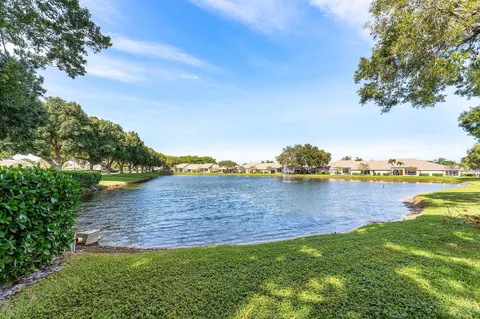 a view of a house with a big yard plants and large trees