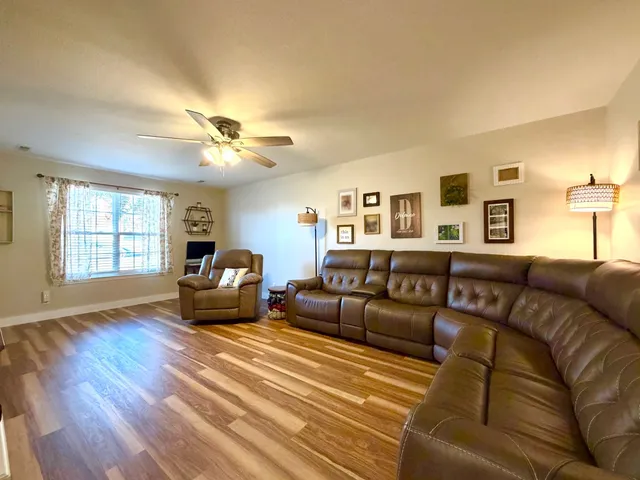 a living room with furniture ceiling fan and a wooden floor