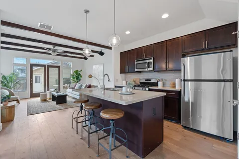 a kitchen with stainless steel appliances granite countertop a refrigerator a sink dishwasher a stove and a refrigerator with wooden floor