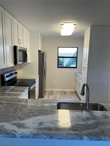 a view of a kitchen with kitchen island a flat screen tv a sink and refrigerator