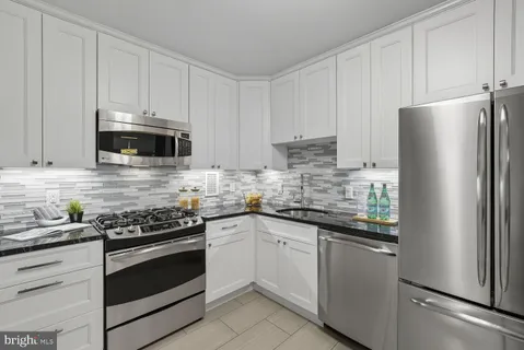 a kitchen with cabinets stainless steel appliances and sink