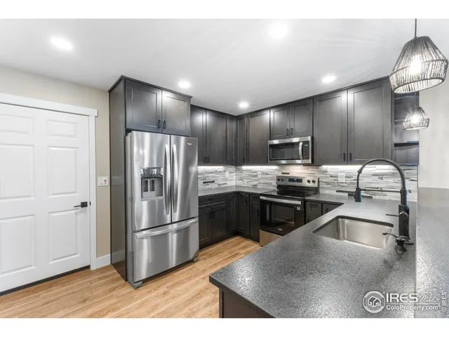 a kitchen with granite countertop a refrigerator and wooden cabinets