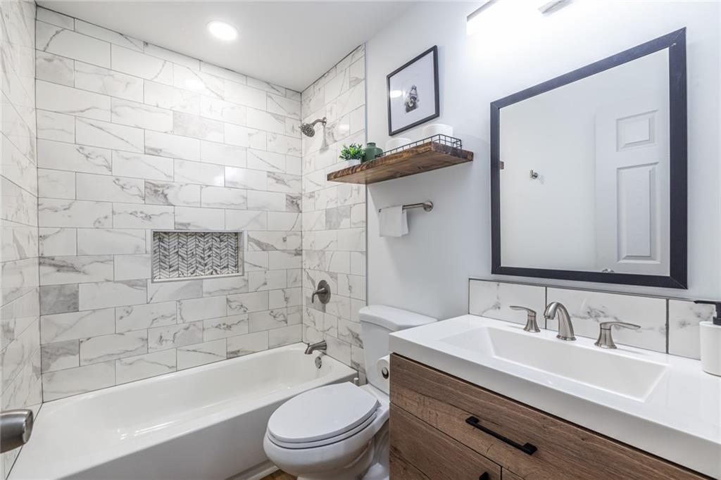 4350 Welcome All, Unit 1 Atlanta, GA 30349 - Photo 13 of 22 a bathroom with a granite countertop sink toilet a mirror a bathtub and shower