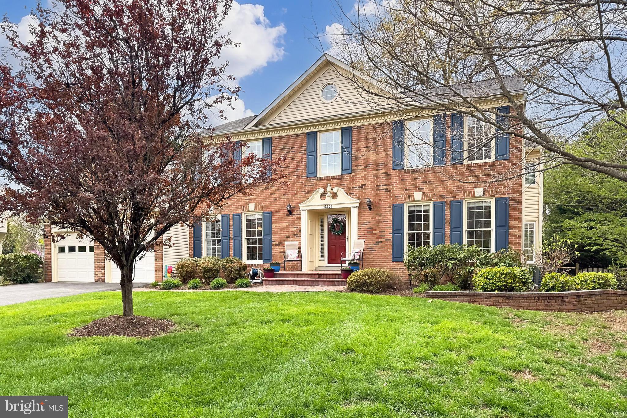 a front view of a house with garden and trees