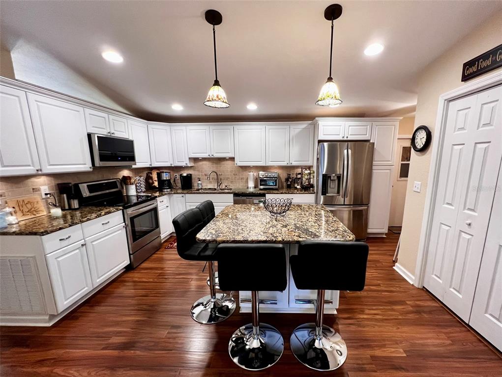 5601 Duncan Road, Unit 96 Punta Gorda, FL 33982 - Photo 6 of 30 a kitchen with stainless steel appliances kitchen island granite countertop a stove a refrigerator a sink a stove a dining table and chairs