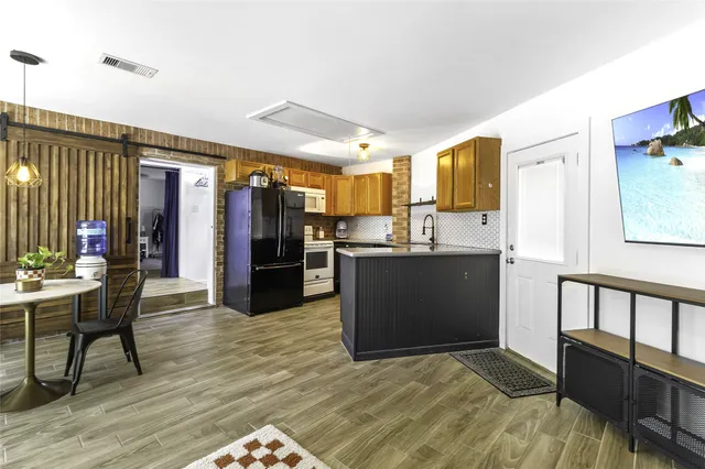 a view of kitchen with stainless steel appliances wooden floor dining table and chairs