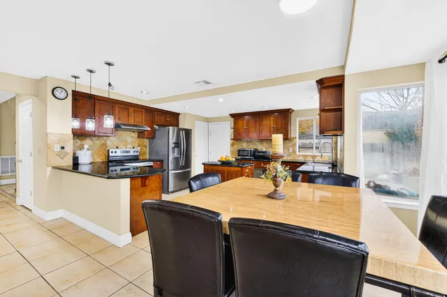 a kitchen with stainless steel appliances granite countertop a sink counter space and a view of living room