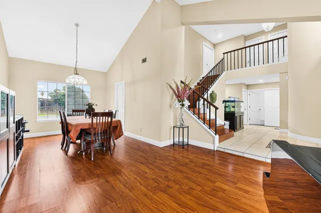 a dining room with wooden floor a chandelier a wooden table and chairs