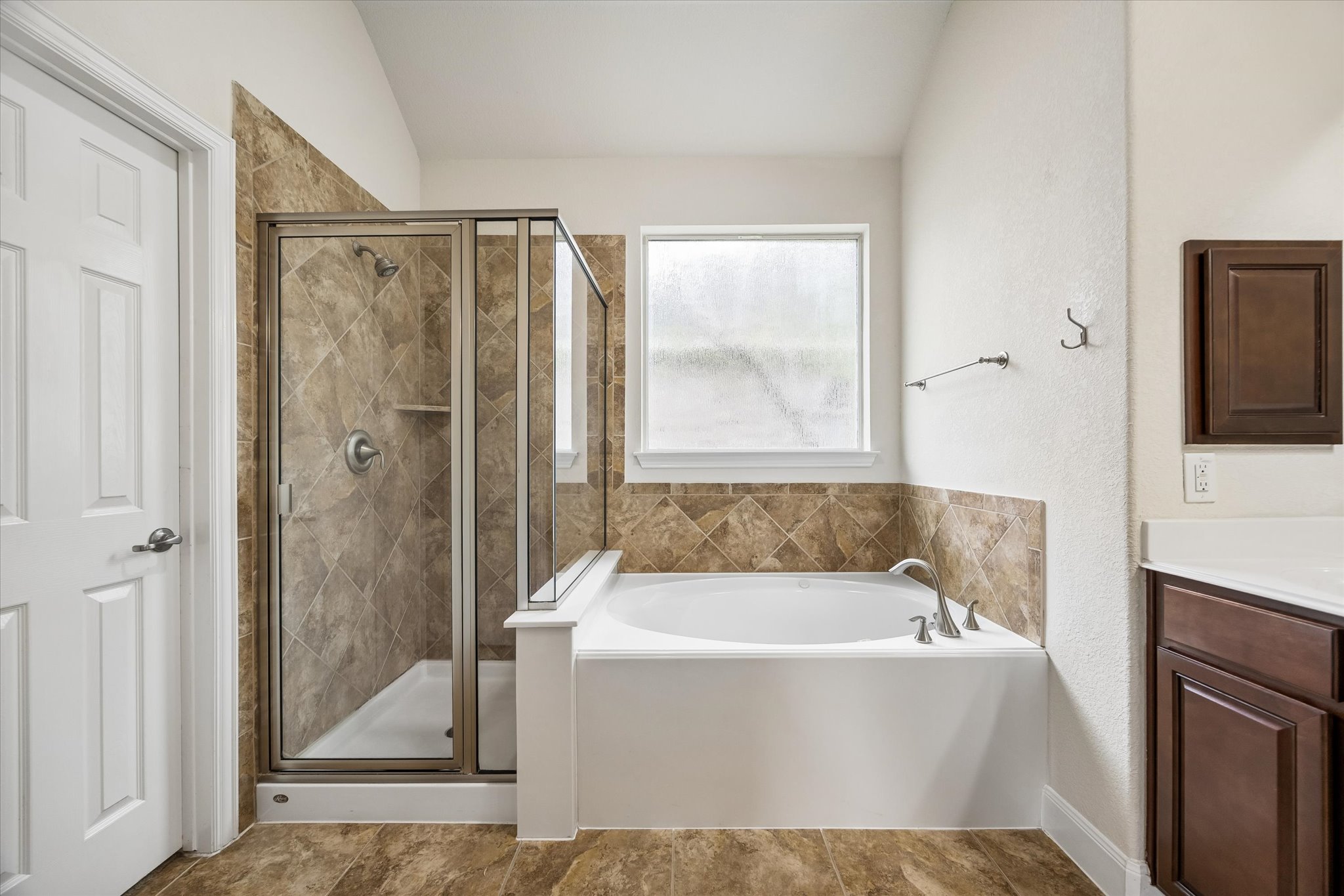 2214 Wembley Way Rosenberg, TX 77471 - Photo 28 of 35 Bathroom featuring a tiled walk-in shower with glass enclosure, a white soaking tub, and a window with frosted glass