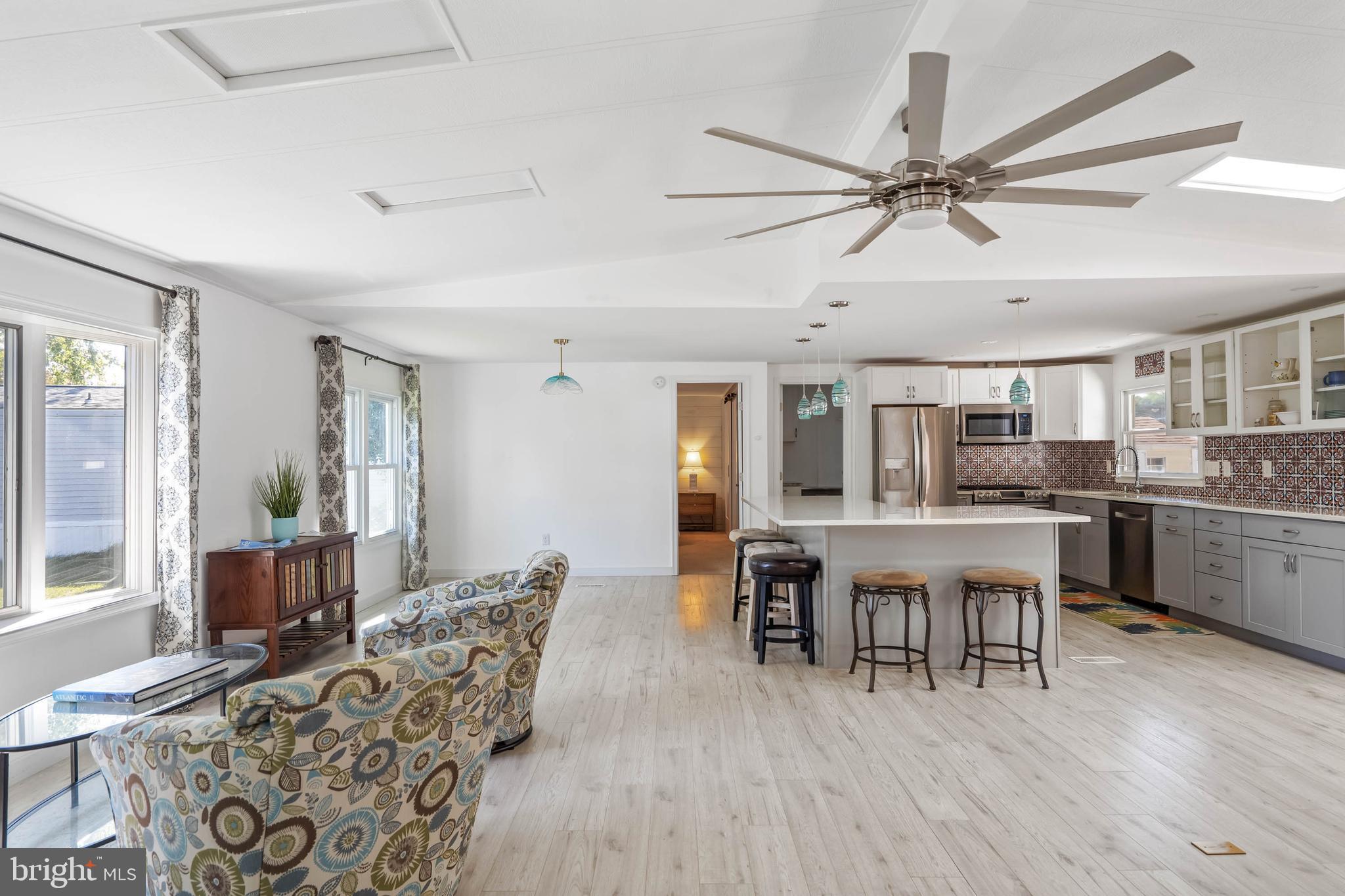 35645 Elk Camp Road Rehoboth Beach, DE 19971 - Photo 12 of 59 a dining room with wooden floor a chandelier fan a wooden table and chairs