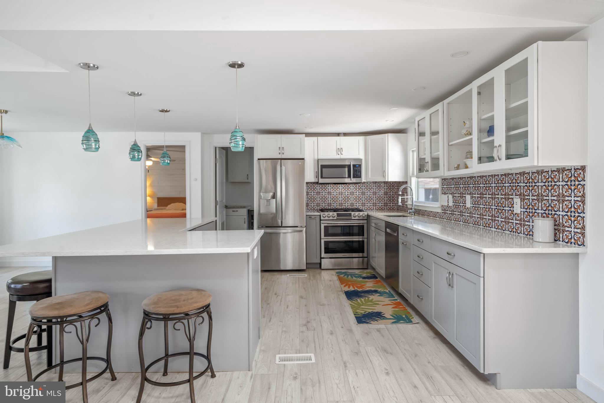35645 Elk Camp Road Rehoboth Beach, DE 19971 - Photo 19 of 59 a kitchen with stainless steel appliances a stove a sink dishwasher a refrigerator and white cabinets with wooden floor