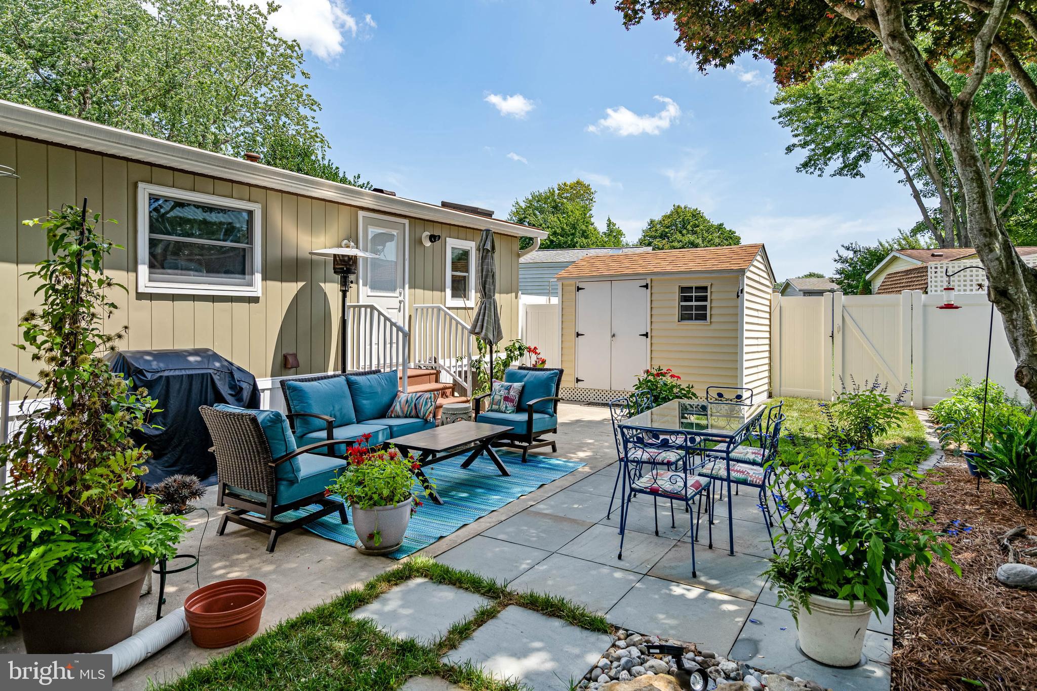 35645 Elk Camp Road Rehoboth Beach, DE 19971 - Photo 6 of 59 a view of a patio with table and chairs potted plants and a large tree