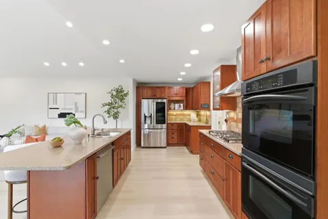 a kitchen with kitchen island granite countertop lots of counter top space a sink and stainless steel appliances