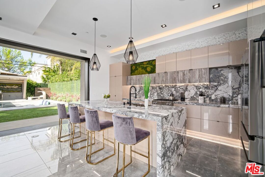 11241 Blix Street Toluca Lake, CA 91602 - Photo 6 of 19 a kitchen with stainless steel appliances granite countertop sink stove and white cabinets next to a window