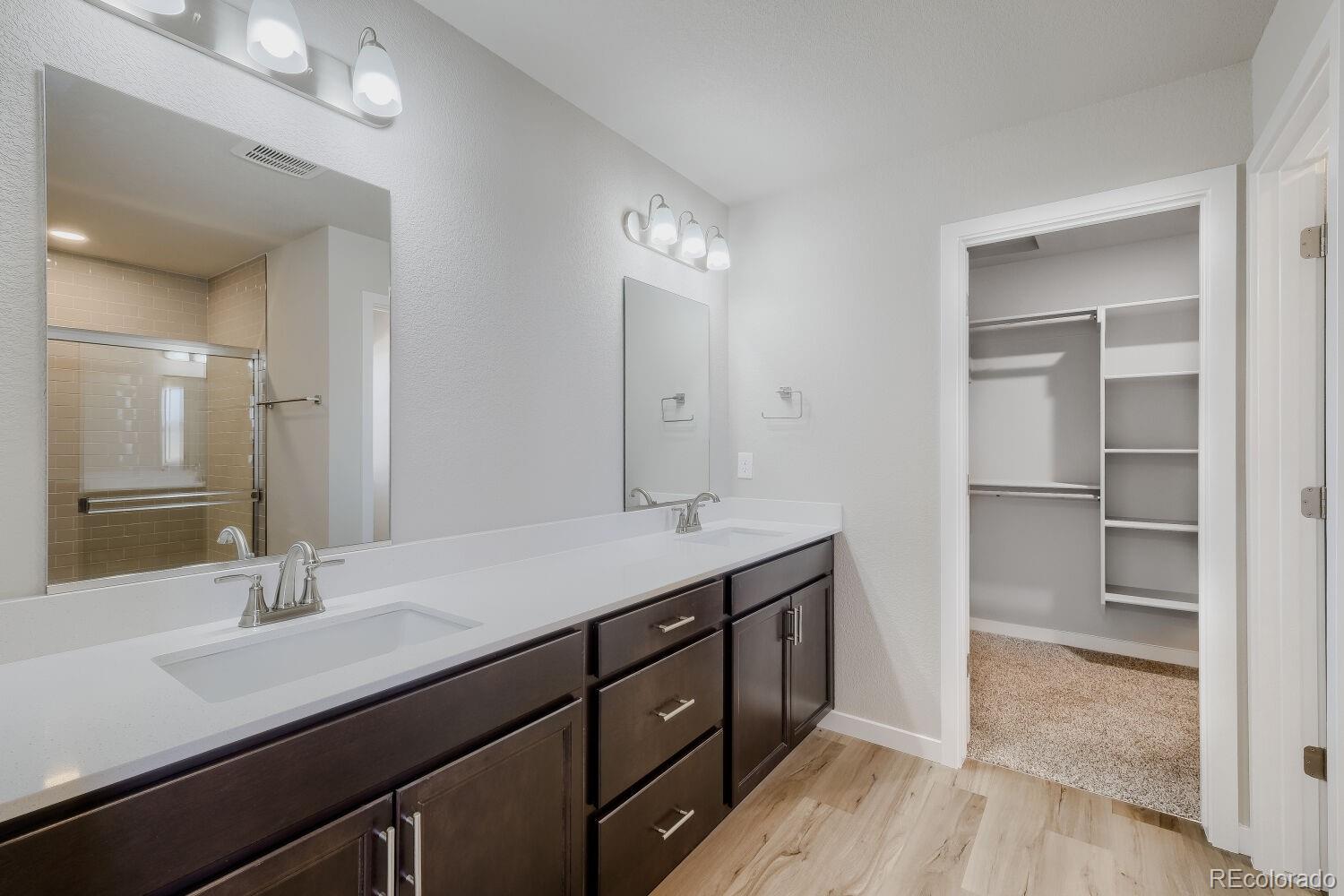 471 Atchison Way Calhan, CO 80808 - Photo 20 of 31 a bathroom with a double vanity sink a mirror and a shower