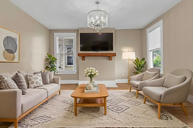 a living room with furniture a flat screen tv and a chandelier