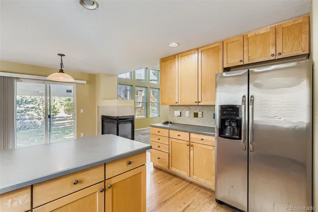 a kitchen with kitchen island granite countertop a refrigerator a sink dishwasher and white cabinets with wooden floor