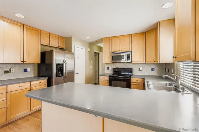 a kitchen with stainless steel appliances granite countertop a refrigerator a stove top oven a sink and cabinets