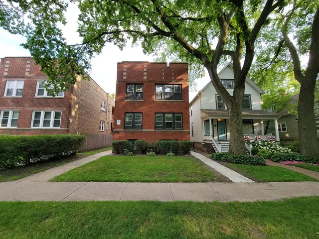 a view of a big yard in front of a brick house with plants
