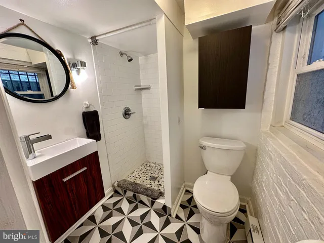 a bathroom with a toilet sink vanity granite and a mirror