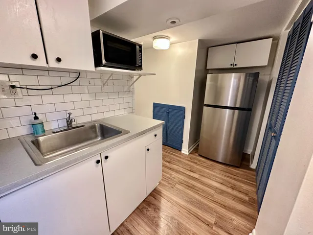 a kitchen with stainless steel appliances a refrigerator a sink and white cabinets